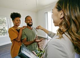 real-estate-agent-handing-clients-a-key-GettyImages-1006937990-1300w-867h