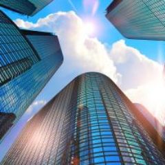 looking-up-at-tall-office-buildings-and-blue-sky-GettyImages-901001432-1300w-867h