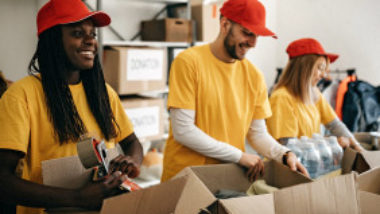 volunteers-in-yellow-shirts-and-red-caps-packing-boxes-gettyimages-1143366552-1300w-867h