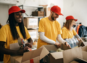 volunteers-in-yellow-shirts-and-red-caps-packing-boxes-gettyimages-1143366552-1300w-867h